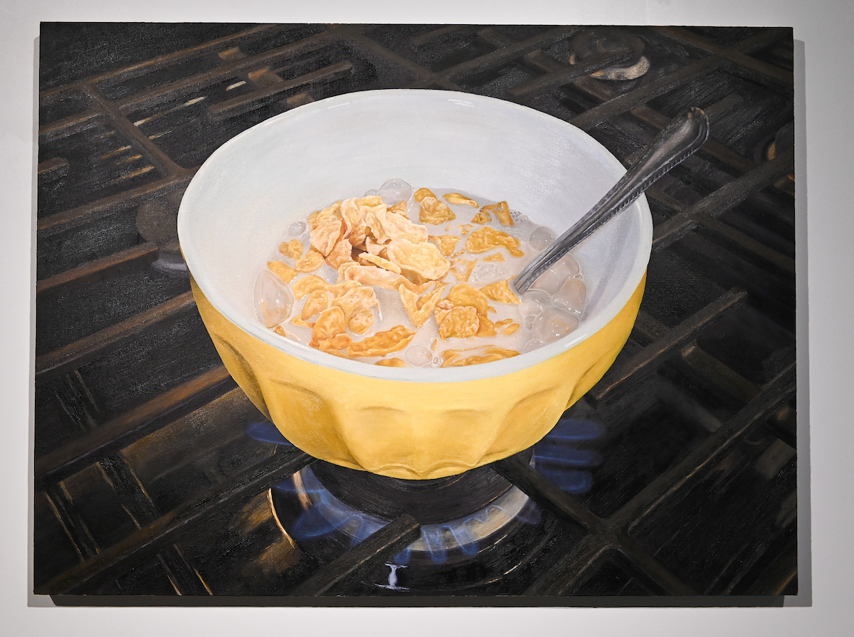 A yellow bowl full of cereal sits on top of a stove burner.