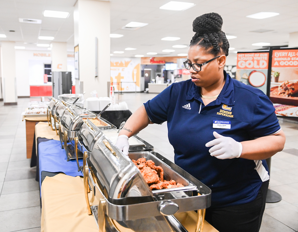 Shelle Ware serves food from an abbreviated hot menu in the University Center on Wednesday, March 18, 2020.
