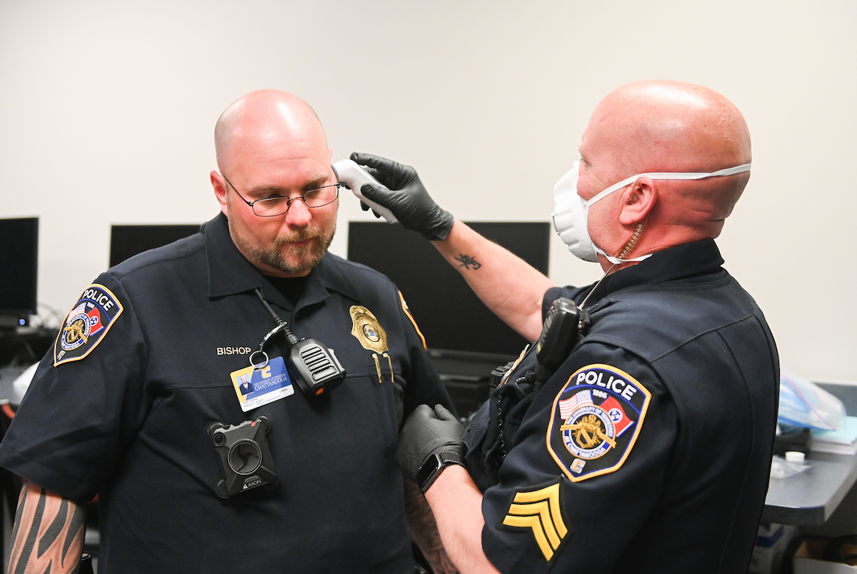UTC Police Sgt. Craig Haney checks the temperature of Officer Scott Bishop on April 2, 2020.