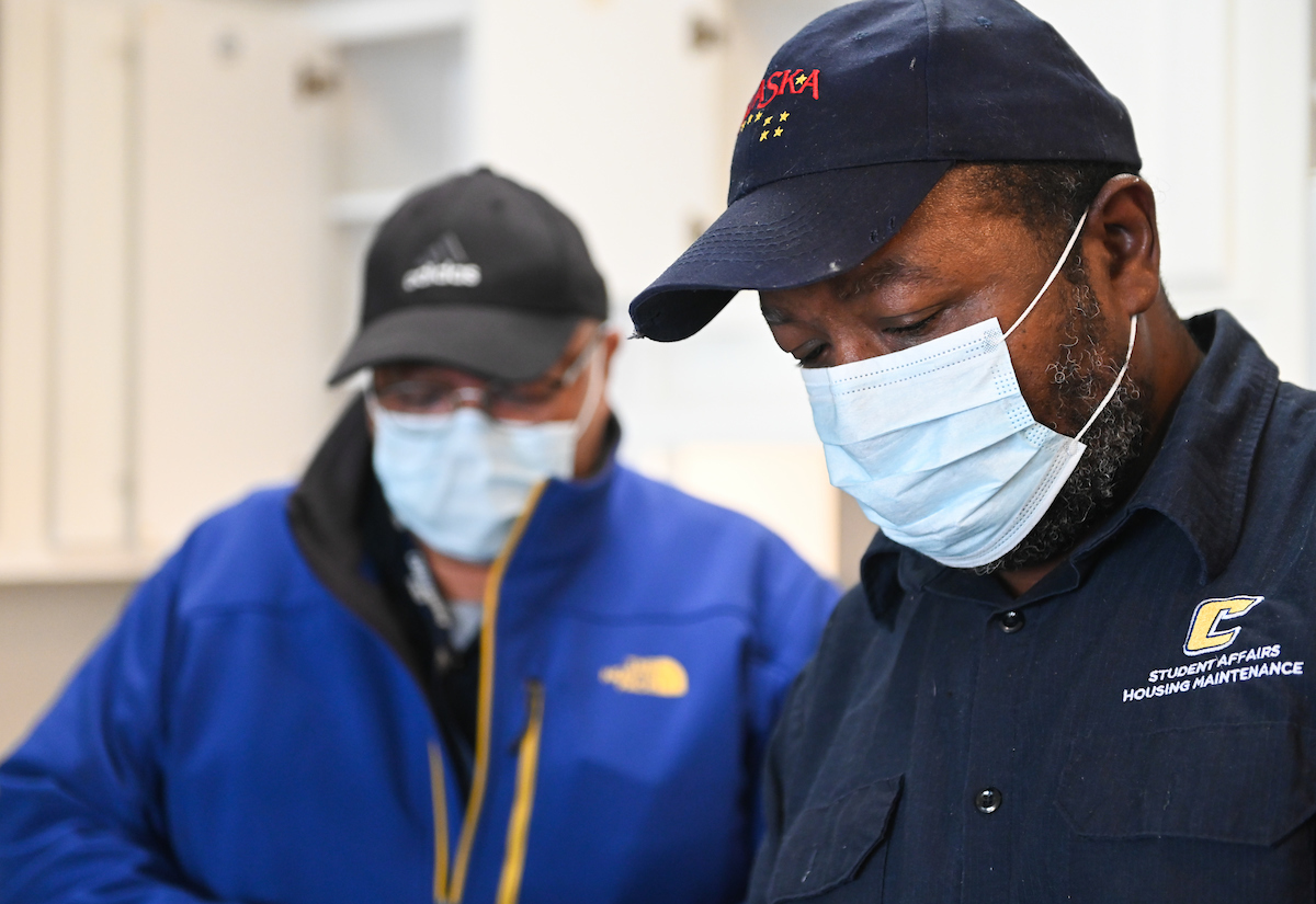 Maintenance workers, from left, Ron Hill and David Lee fix equipment on April 2, 2020.