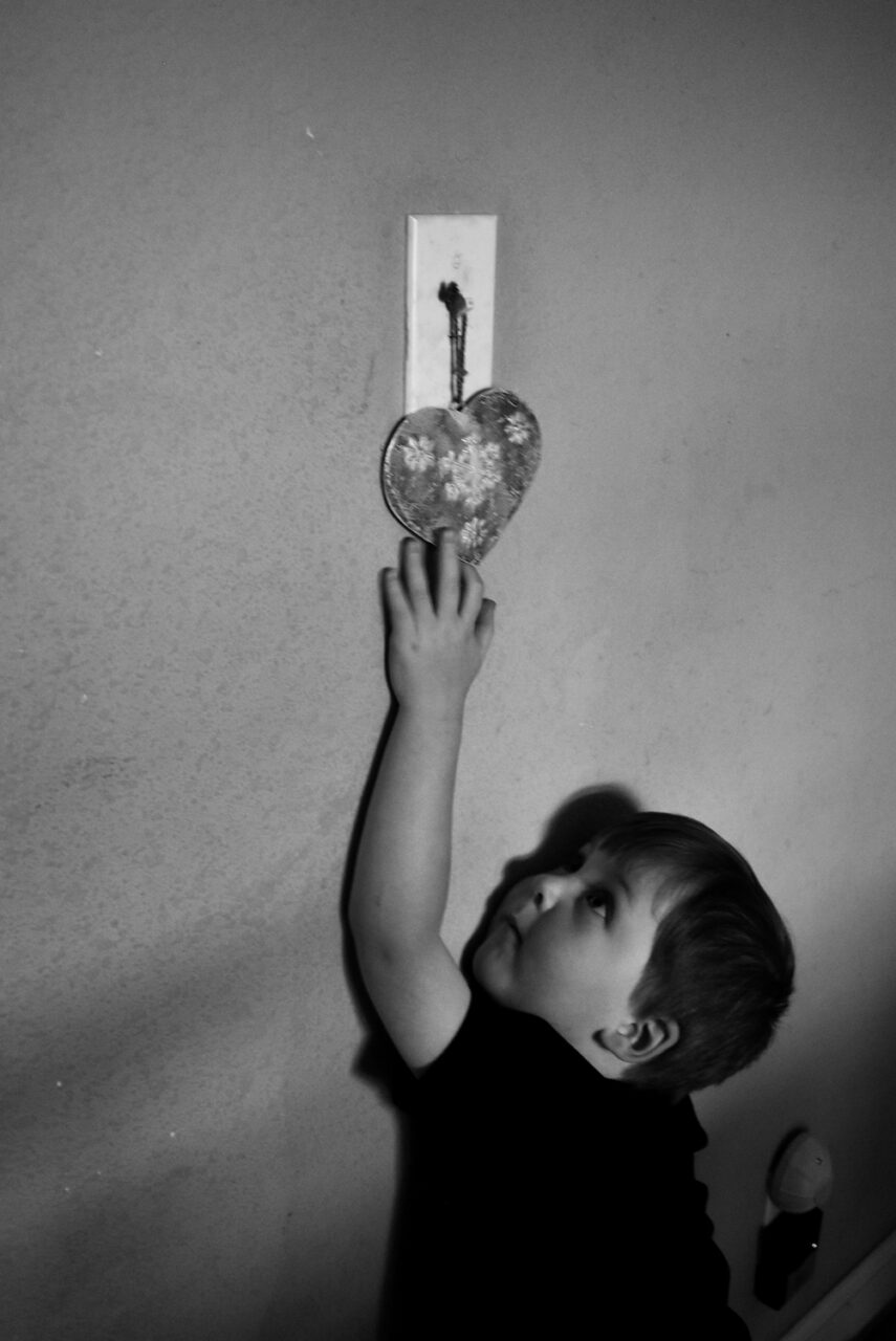 Fielder Lee hangs Christmas ornaments on light switches.