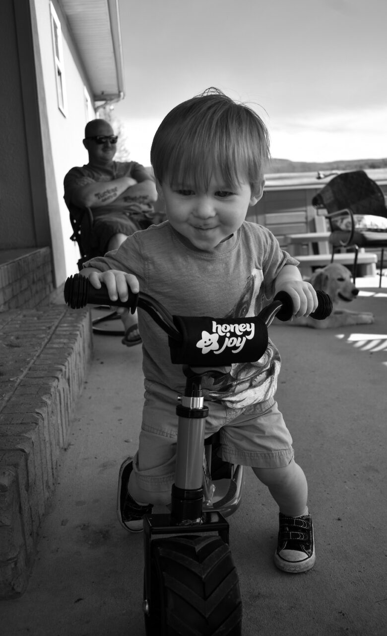 Tucker Jude Richardson tries to run over Amanda Fann's toes with his tricycle.