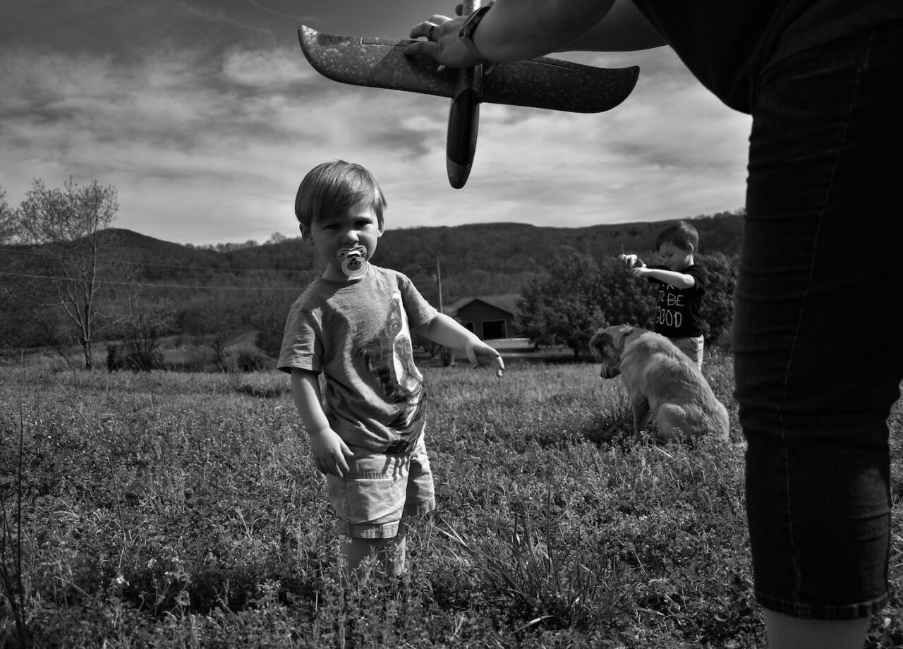 Alicia Richardson shows her sons how to fly a toy airplane.