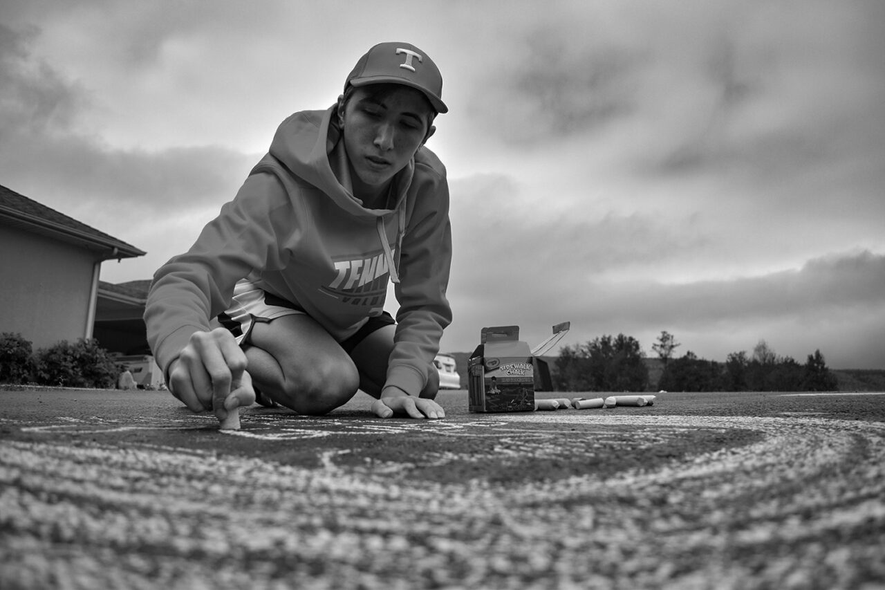 Rian Scott Fann chalks messages on the driveway of his home in Dunlap, Tennessee.