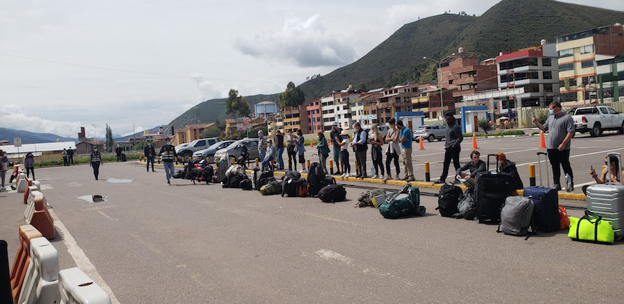 People wait in line at the Cuzco airport to board a plane out of the country.
