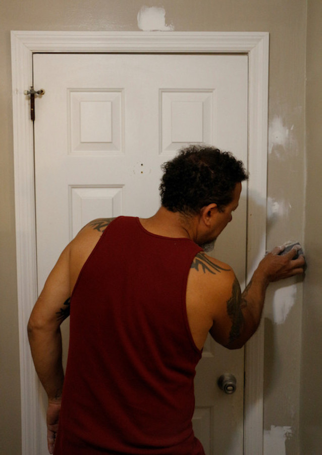 Marcus Ratcliff sands down patches of spackling. He was repairing blemishes to the bathroom wall as part of his renovation project.