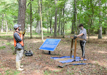 Assistant Professor Morgan Smith uses a GPS device to pinpoint exactly where the holes have been dug.