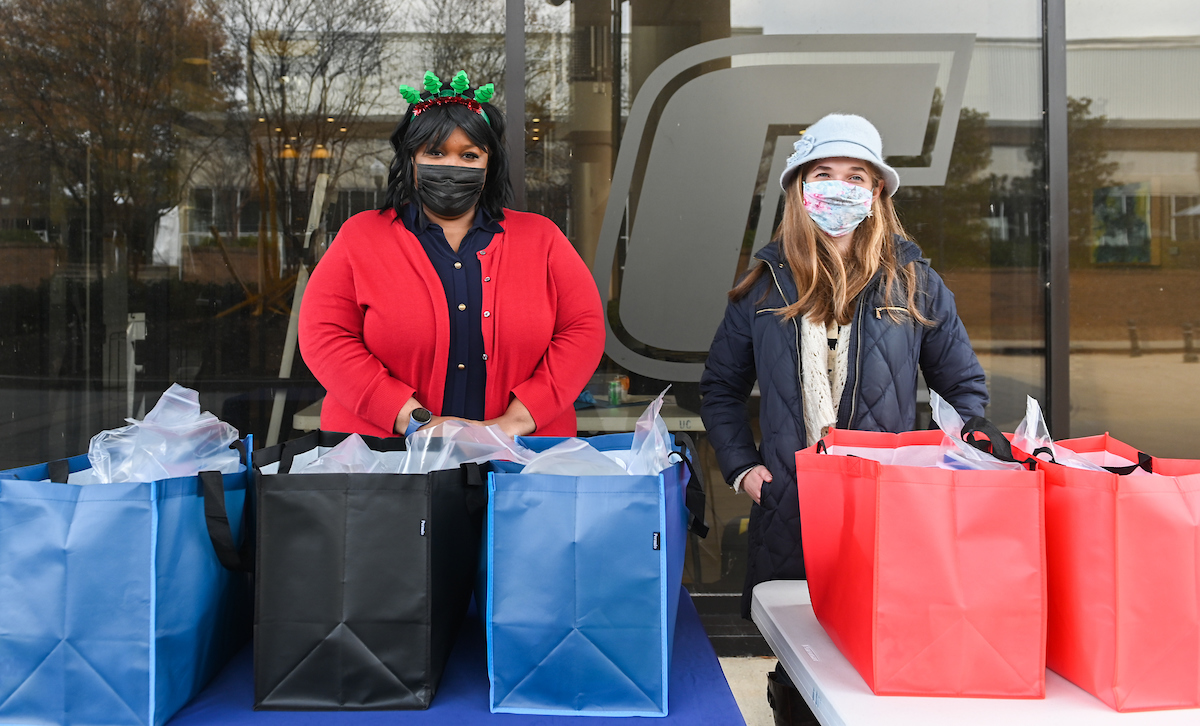 Squoia Holmes, wearing red, and Laney Wood hand out bags full of snacks and necessities Thursday, Dec. 17, 2020 at the University Center.