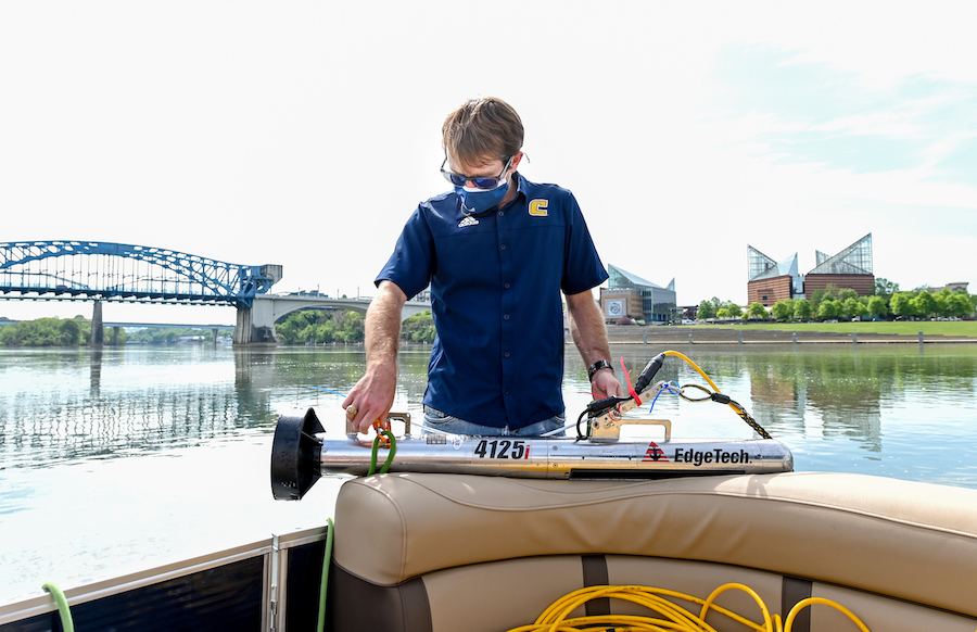 Assistant Professor Morgan Smith makes adjustments to the towfish, the device that emits sonar signals.