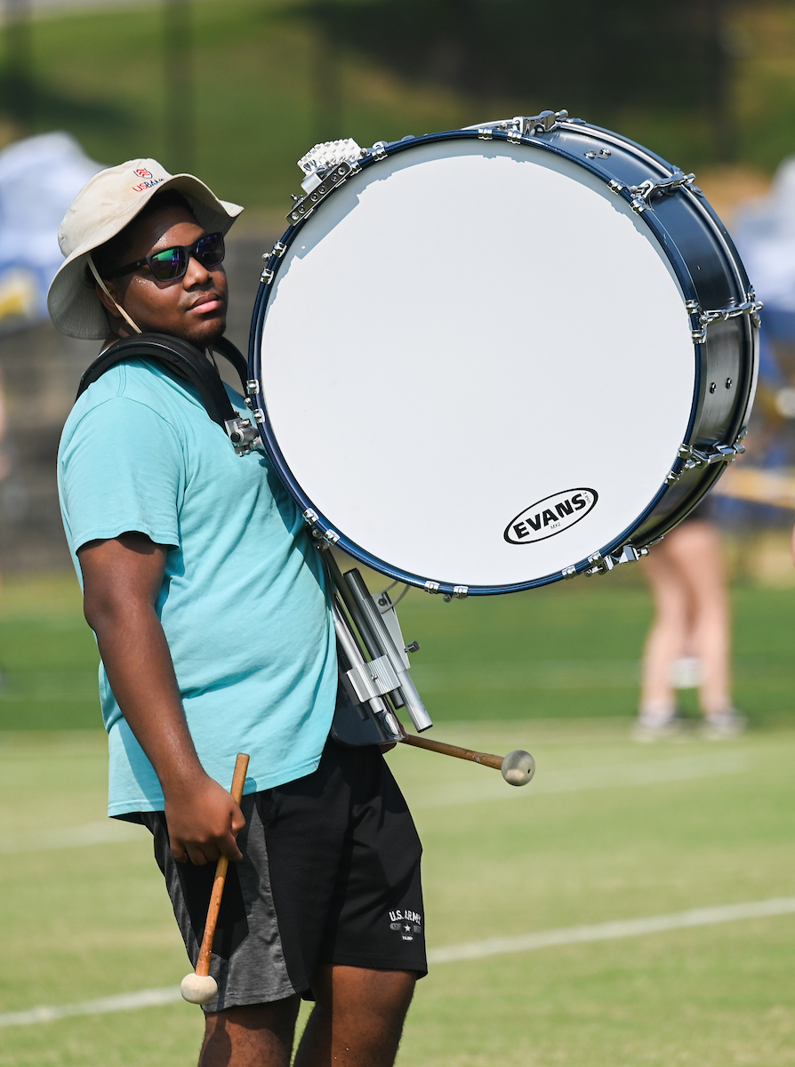 Marching Mocs member plays a large bass drum outdoors.