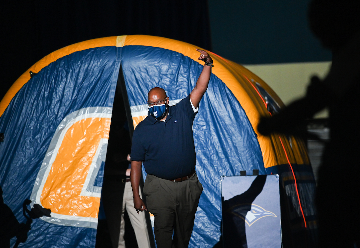 Man walking out of tunnel with "Power C" on it, raising his hand holding up the "Power C".