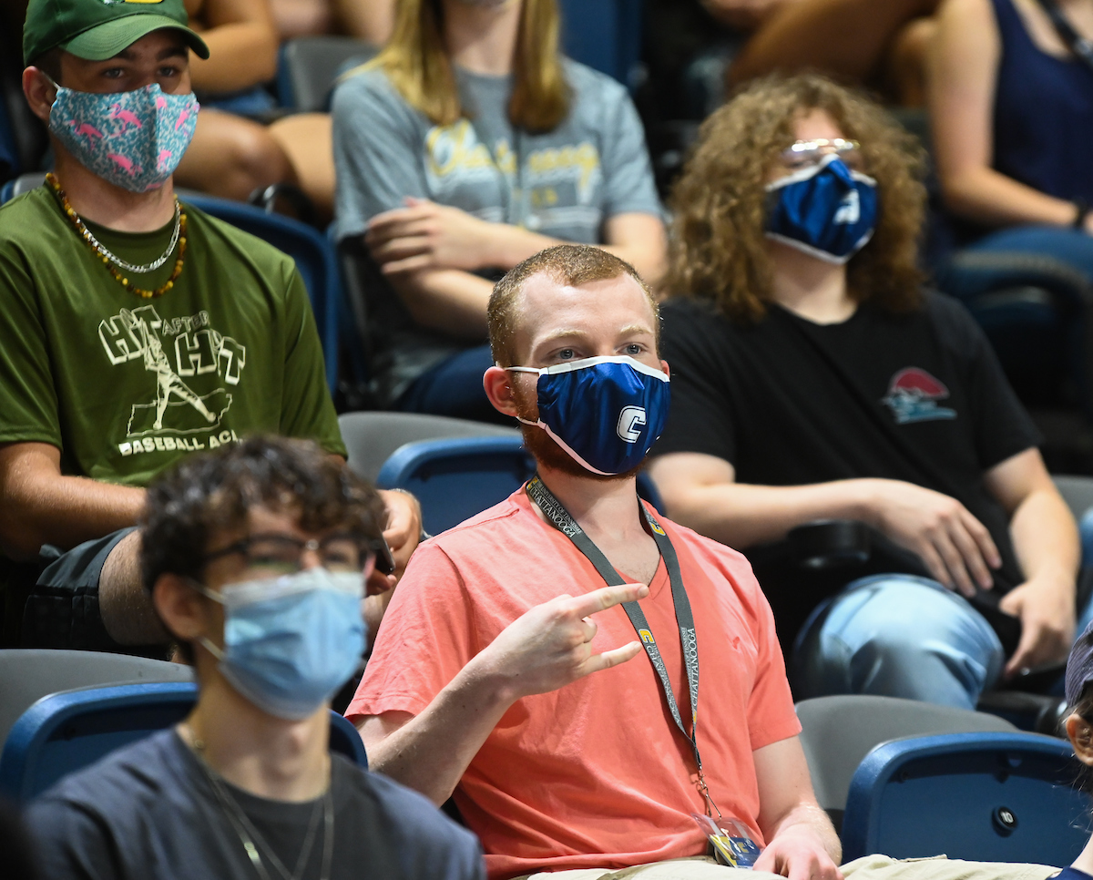A group of students sitting in the McKenzie Arena, one holding up the "Power C".