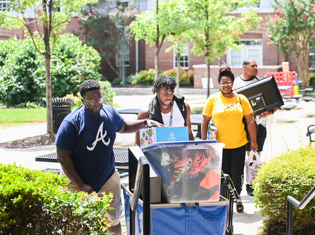 Family carries dorm items and boxes during Operation Move-In.