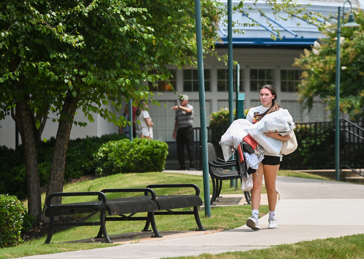 Student carries belongings to dorm, during Operation Move-In.