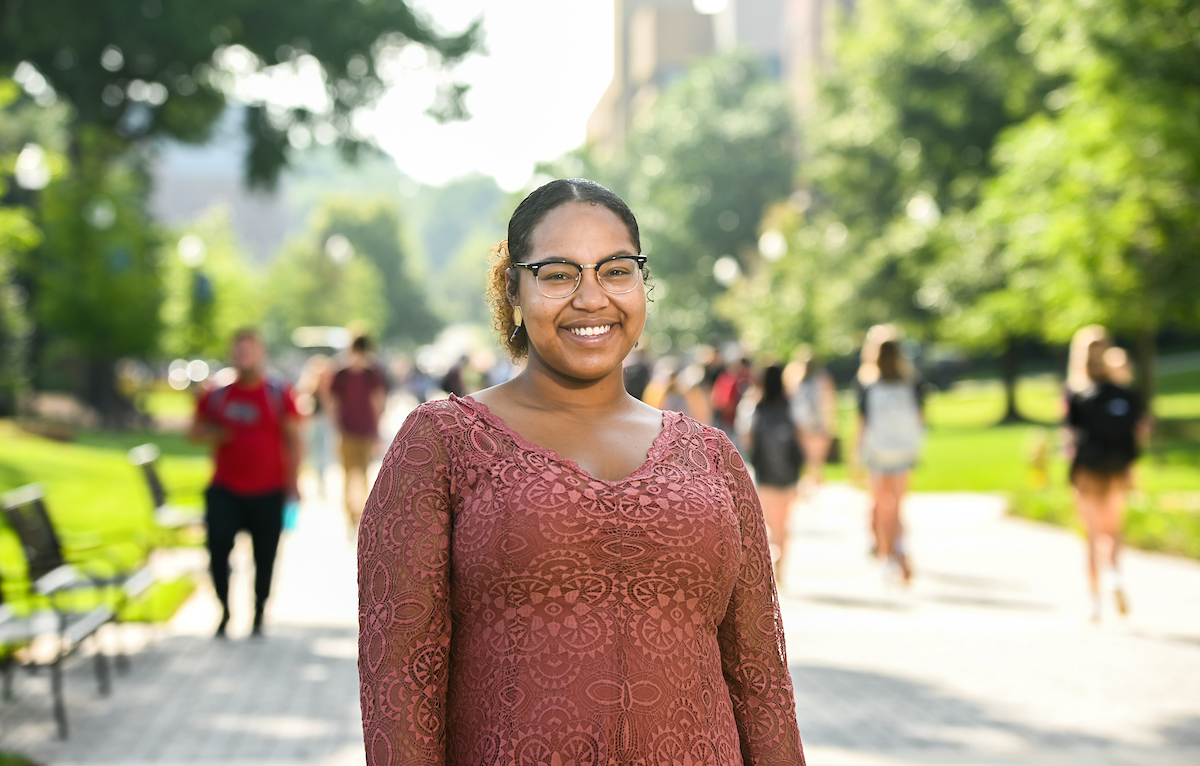 Akeyla Madison poses for photo with campus scene and walking students in background