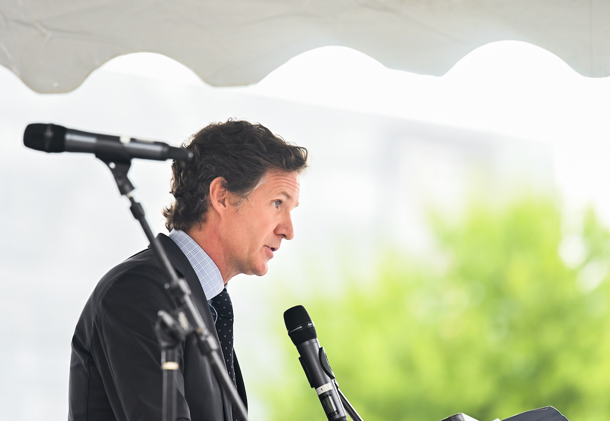 Chattanooga Mayor Tim Kelly speaks into a microphone at a podium. Another microphone is visible in the foreground.