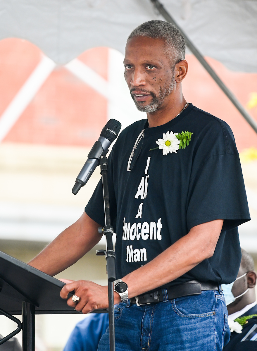 LaFrederick Thirkill speaks at a podium with a microphone, under a tent.