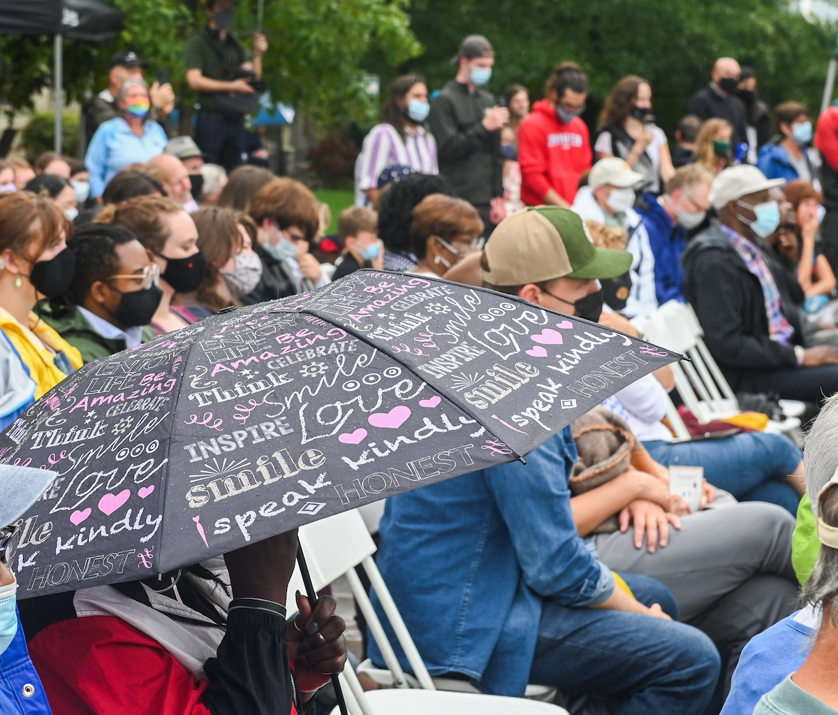 Audience seated outdoors, focusing on the speaker.