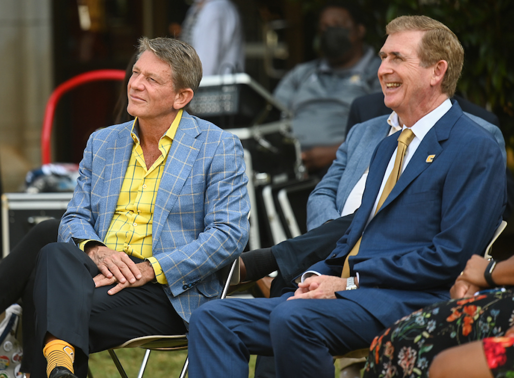 Two men sitting outdoors, smiling and engaged.