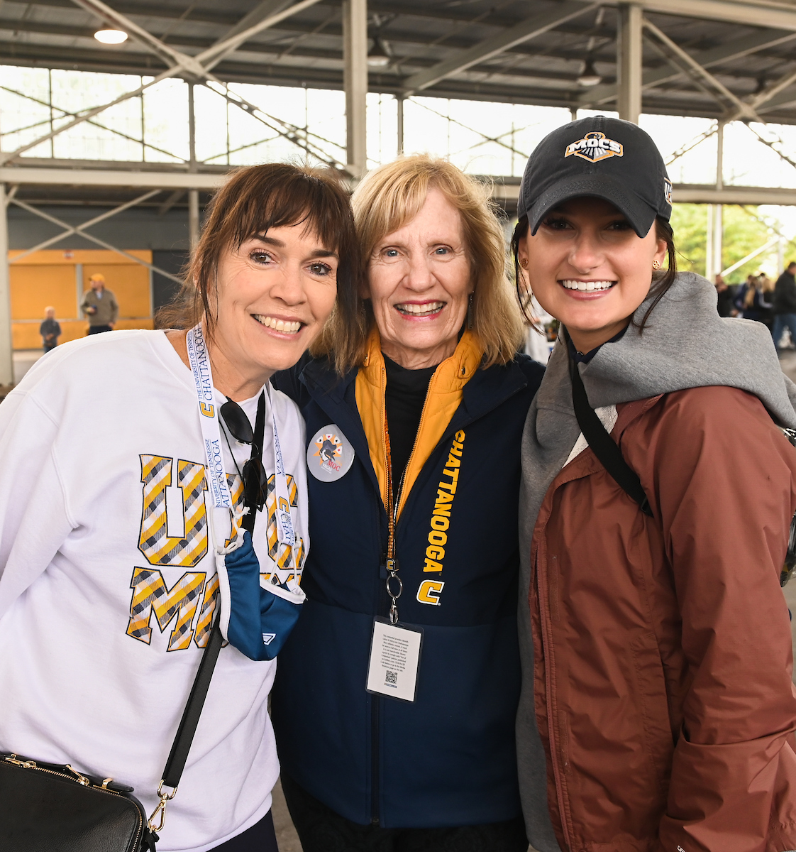 Three women smile warmly at the camera, standing closely together.