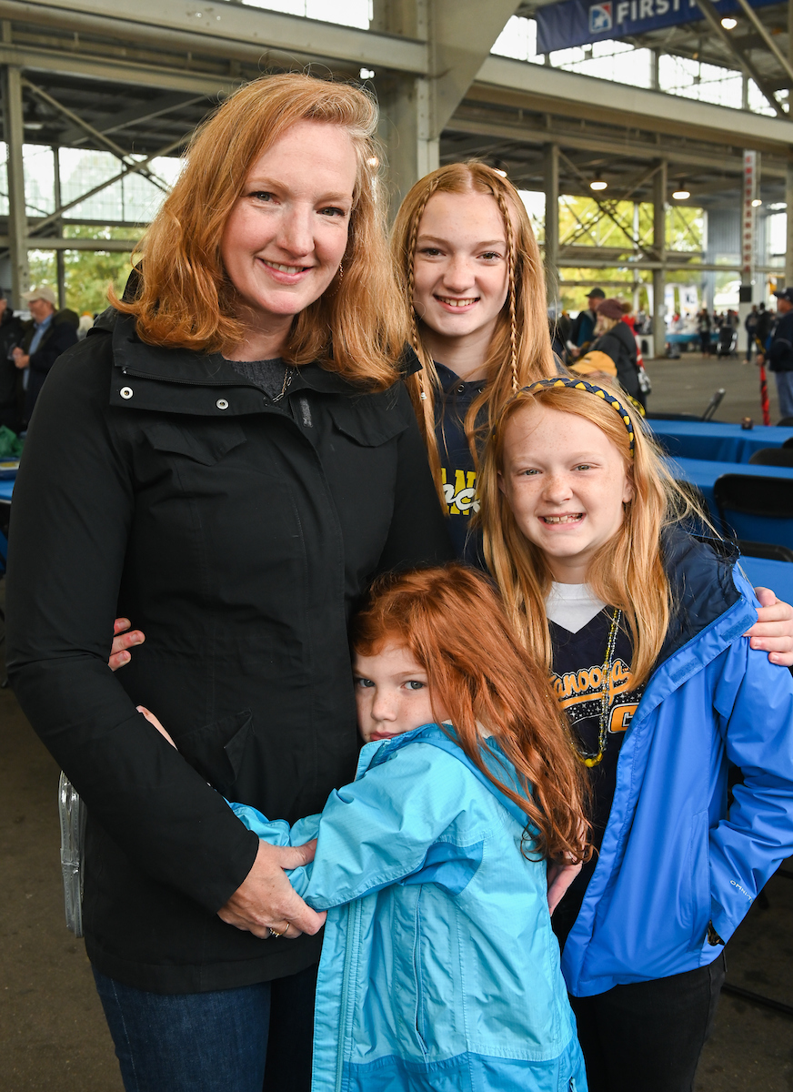 A smiling woman stands with three young girls in the football stadium.