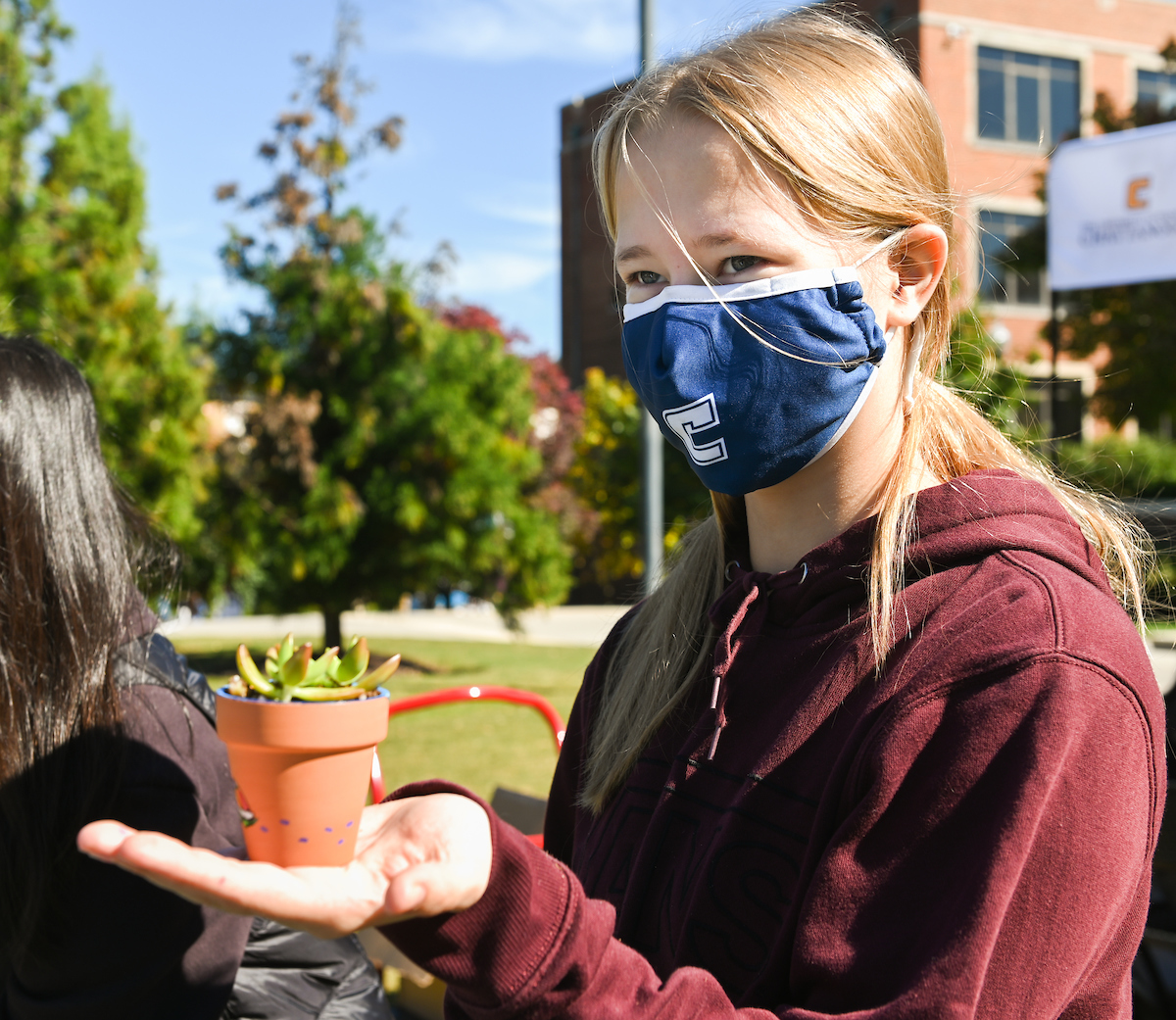 A student holding a small pot with a succulent.