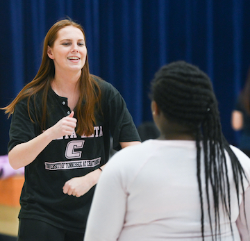 A student smiles and gestures while talking to another person.