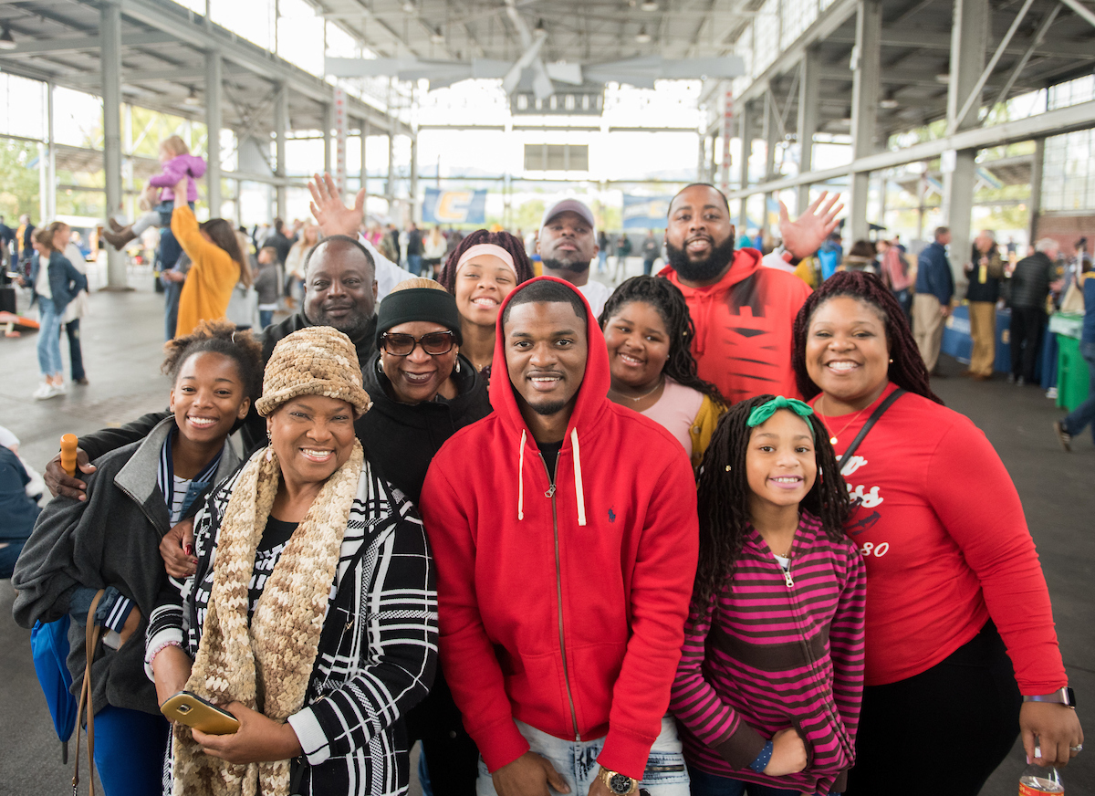 A family smiling warmly poses indoors at a football game.