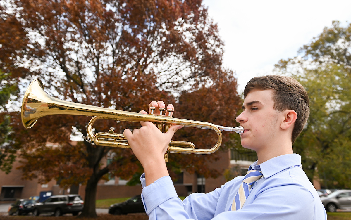 A man plays a trumpet outdoors.