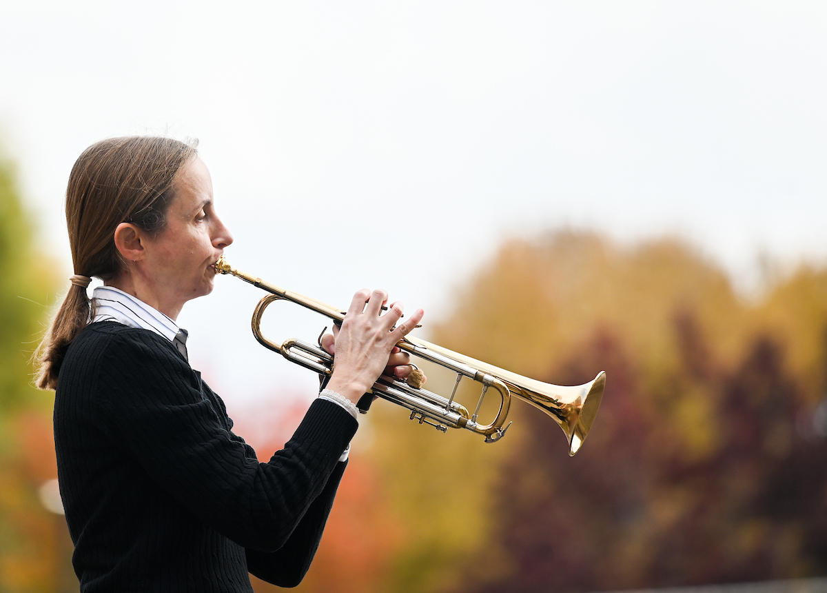 Woman plays trumpet outdoors.