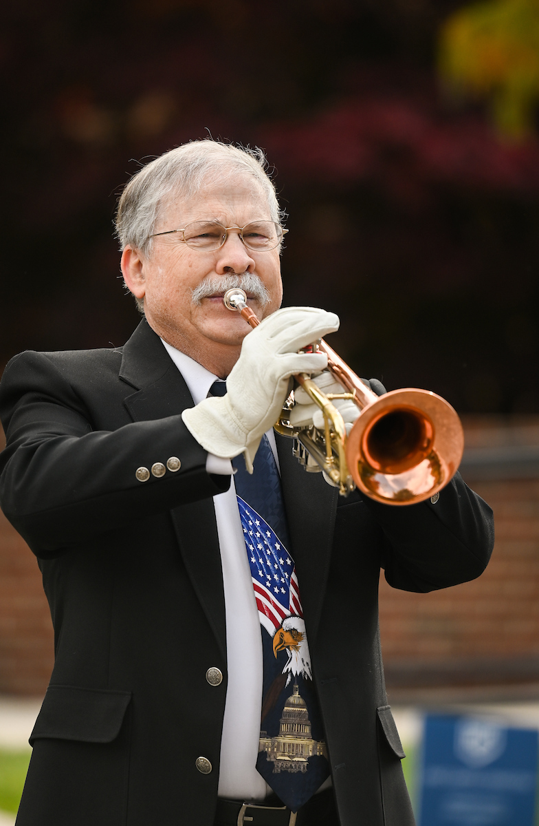 Man plays trumpet outdoors.
