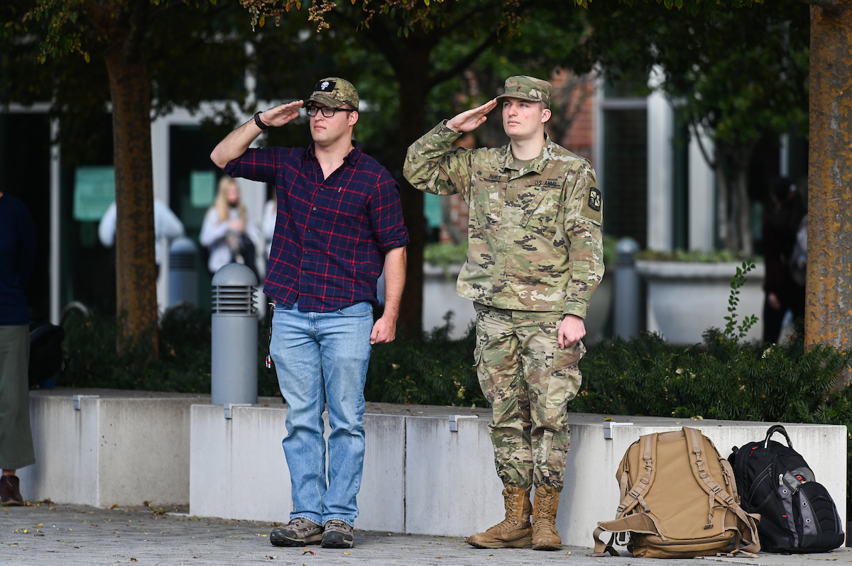Two men standing and saluting, one in military uniform.