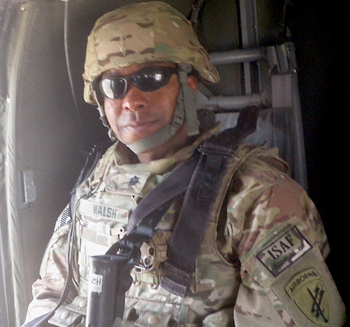 Darell Walsh in military uniform and helmet sits in a helicopter, wearing sunglasses.
