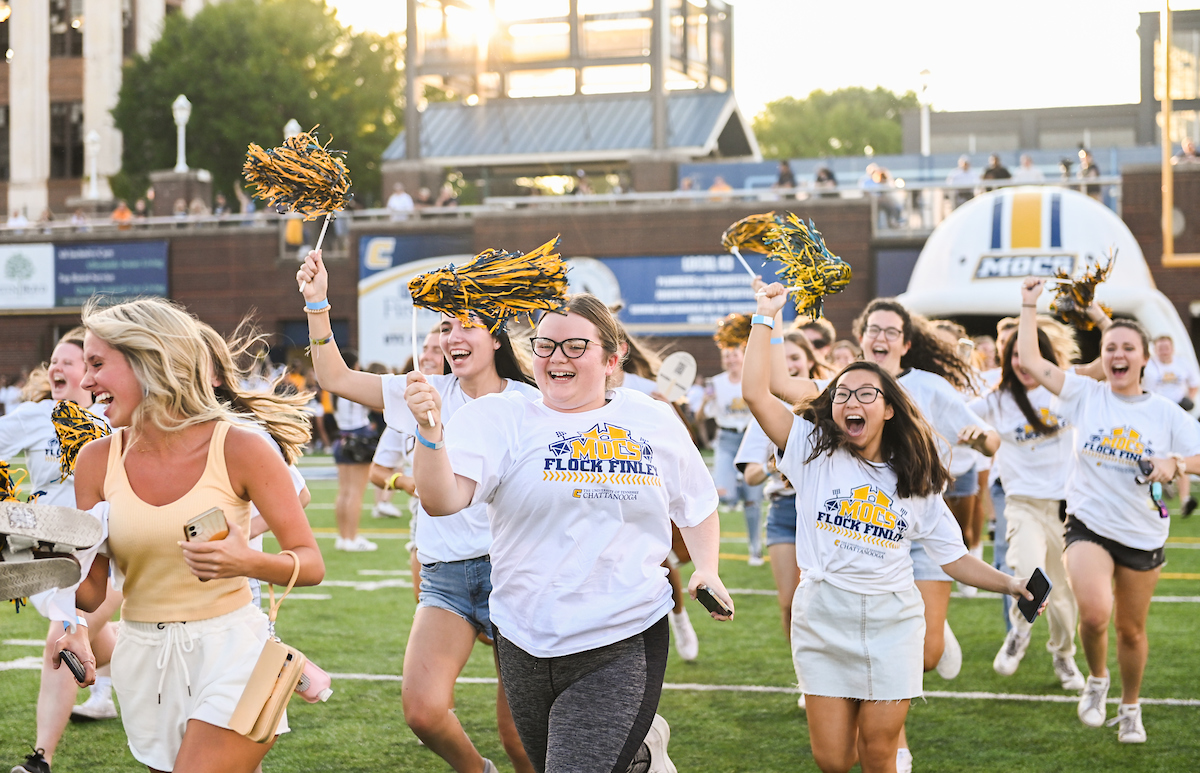 Students run across the field at Finley Stadium as part of the Mocs Flock Finley event before the first football game of the season.