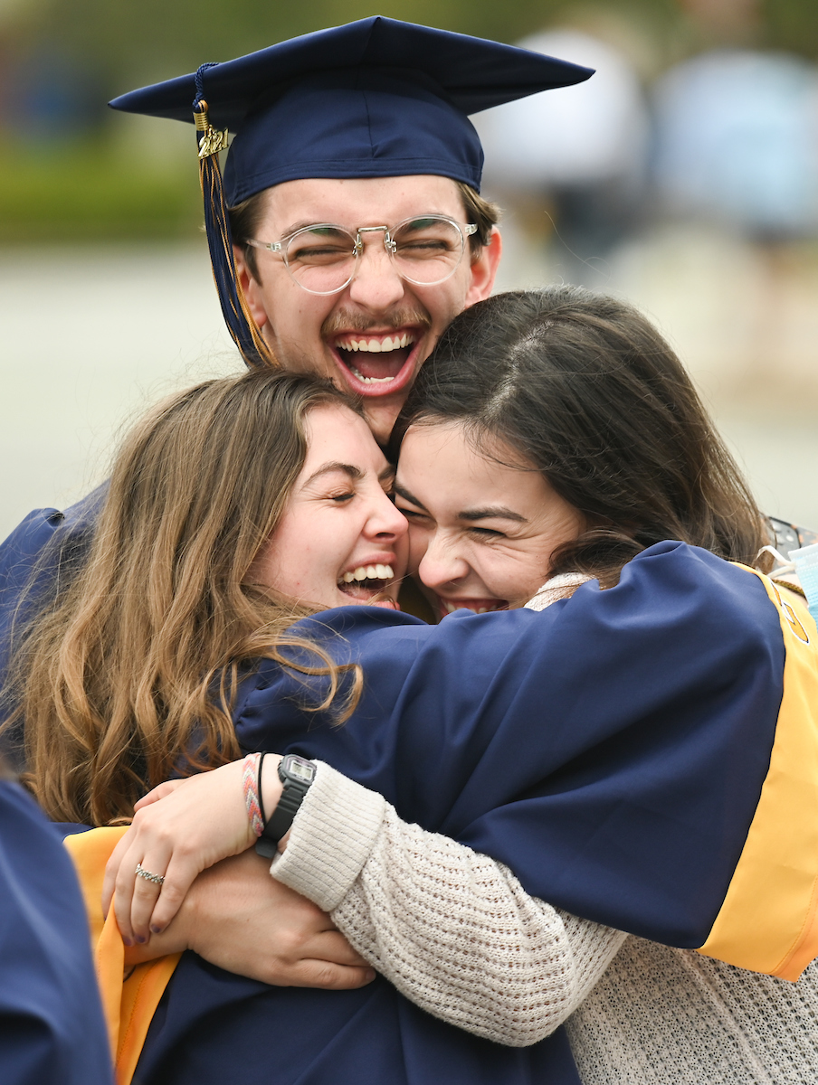 Alex Peppers, center, hugs Hope Cody, left, and Margo Zani after the seventh of nine graduation ceremonies on Saturday, April 24, in McKenzie Arena.