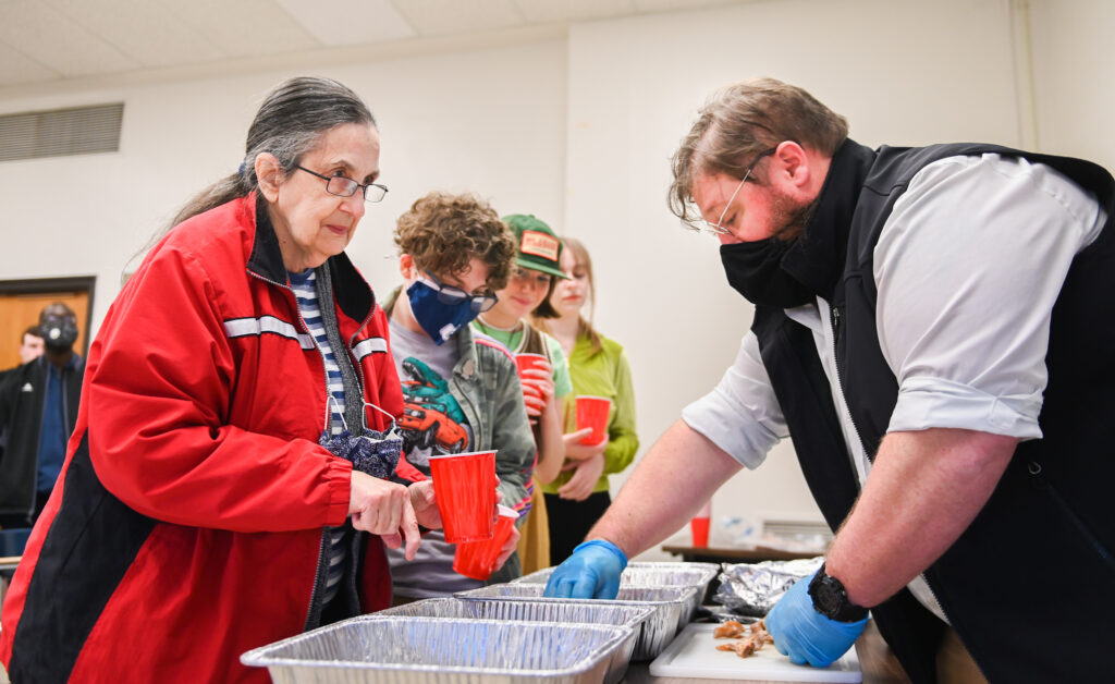 Students in “Food and Southern History,” including Pat Ormond, left, wait to receive different types of cured bacon from guest instructor James Scott.