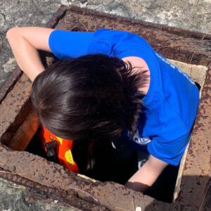 Jillian Saraney enters a well to collect water samples. Photo by Emory Evans.