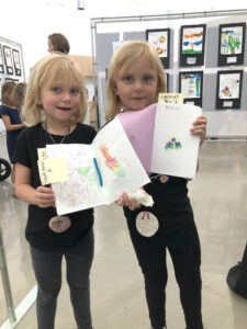 Twins Lou and Evelyn Bohannon show off samples of their work at the kindergarten art exhibition. All photos courtesy of Angela Dittmar/Arts-Based Collaborative.