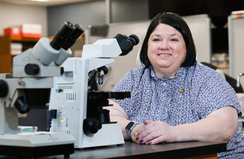 Gretchen Potts (sitting in a biology lab), UC Foundation Professor of Chemistry and the department head for Biology, Geology and Environmental Science, is celebrating her 20th anniversary at UTC. Photo by Angela Foster.