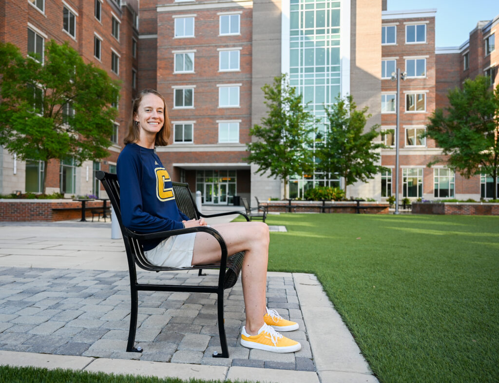 Liz Hathaway sits on a bench in the West Campus housing courtyard. Hathaway, a UC Foundation assistant professor of kinesiology, assumes the West Campus faculty in residence post as the fall semester begins. Photo by Angela Foster.