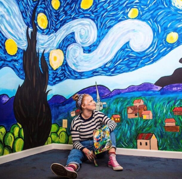 Corinna Lingle sits in front of her mural of Vincent van Gogh's "Starry Night."