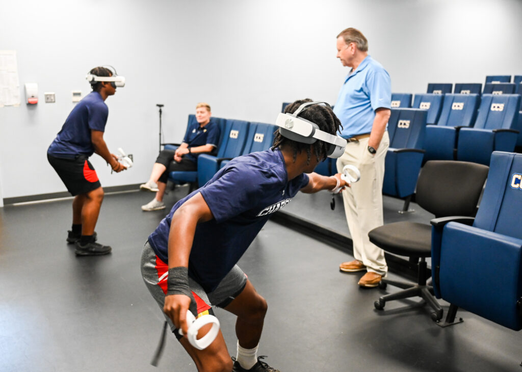 Two Chattanooga Christian School athletes using VR equipment under the watchful eyes of Lynette Carlson (sitting) and Gary Wilkerson (standing).