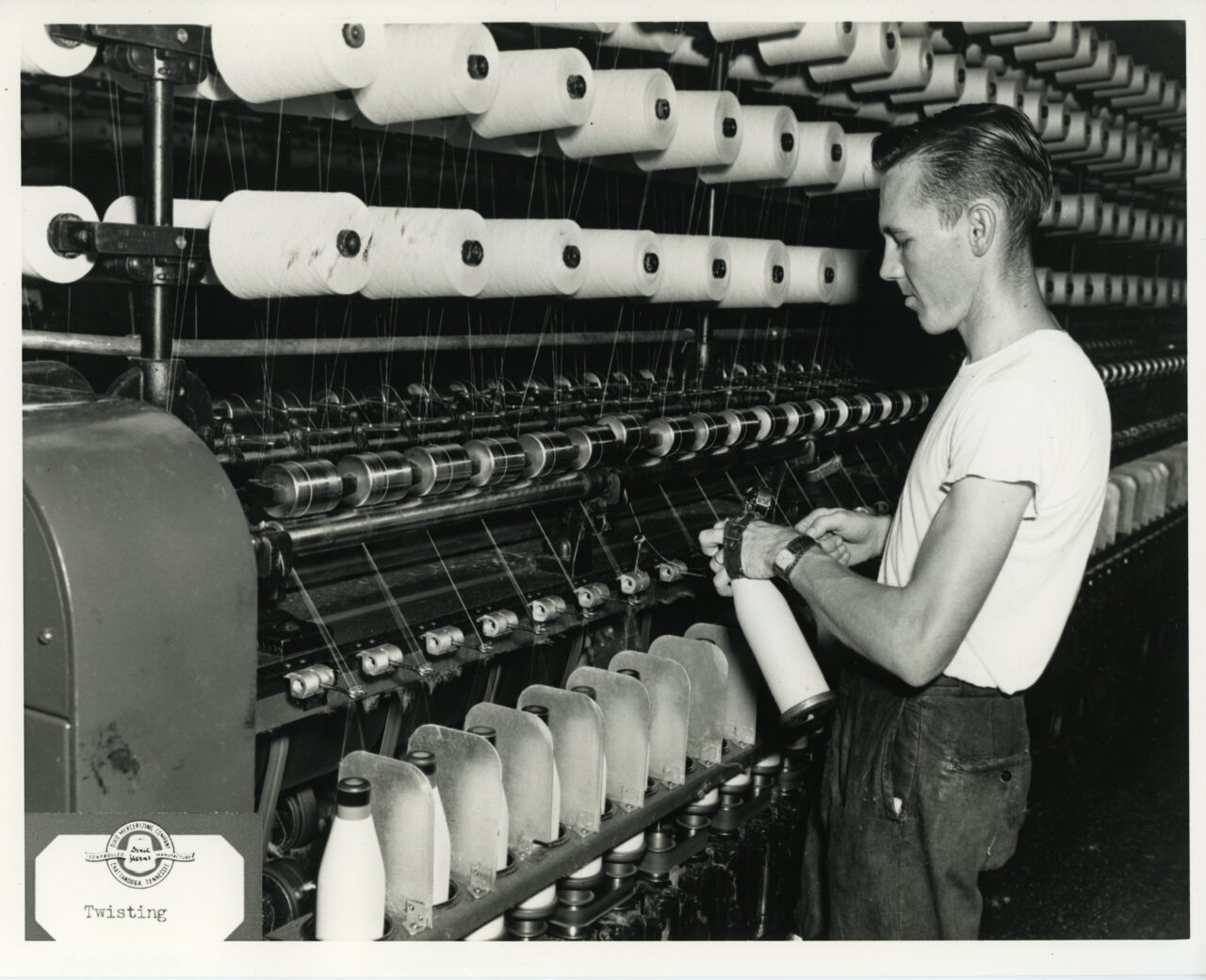 Photograph depicting an employee working among spools of yarn in a Dixie Mercerizing Company plant, Chattanooga, Tennessee. The photo is labeled: "Twisting."