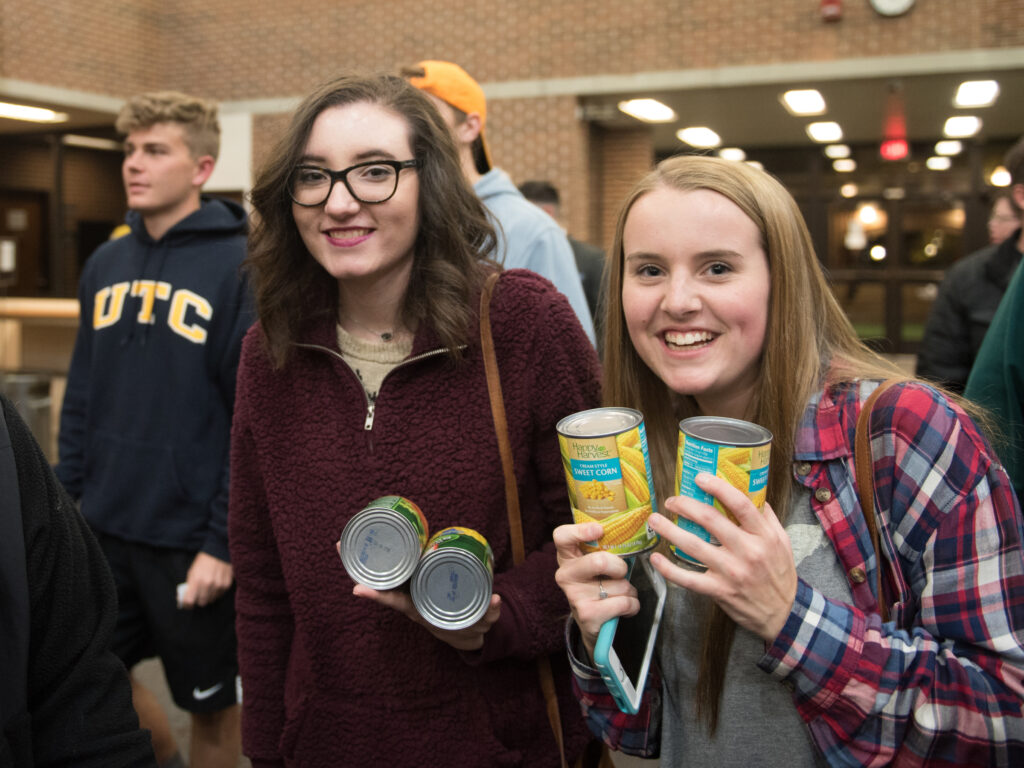 UTC students holding two cans of food before going into the Beat Hunger concert.