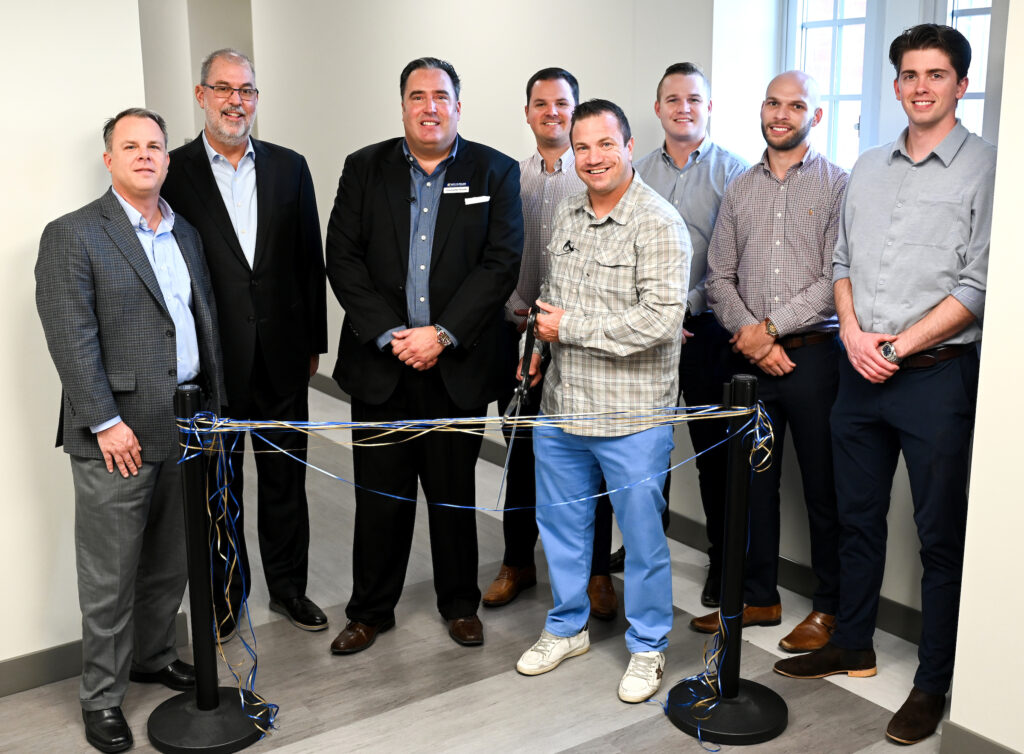 Ribbon cutting for Sales Institute in Fletcher Hall, Wednesday, Nov. 2, 2022. From left: Gary W. Rollins College of Business Associate Dean Michael Jones, Dean Robert Dooley, Professor Christopher Plouffe, Logan Glasscock (producer, Insurance Group Of America), Jamie Noe (CEO, IGA, holding scissors), Charley Myers (partner, IGA), James Myers (producer, IGA) and William Slatten (producer, IGA). Photo by Angela Foster.