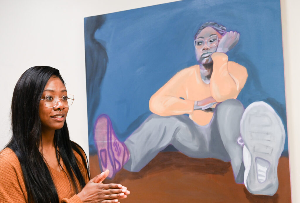 Tamia Spinks discusses her oil painting, "Muddled," at the Dec. 12 opening of the Diversity and Engagement Art Gallery. Photo by Angela Foster.