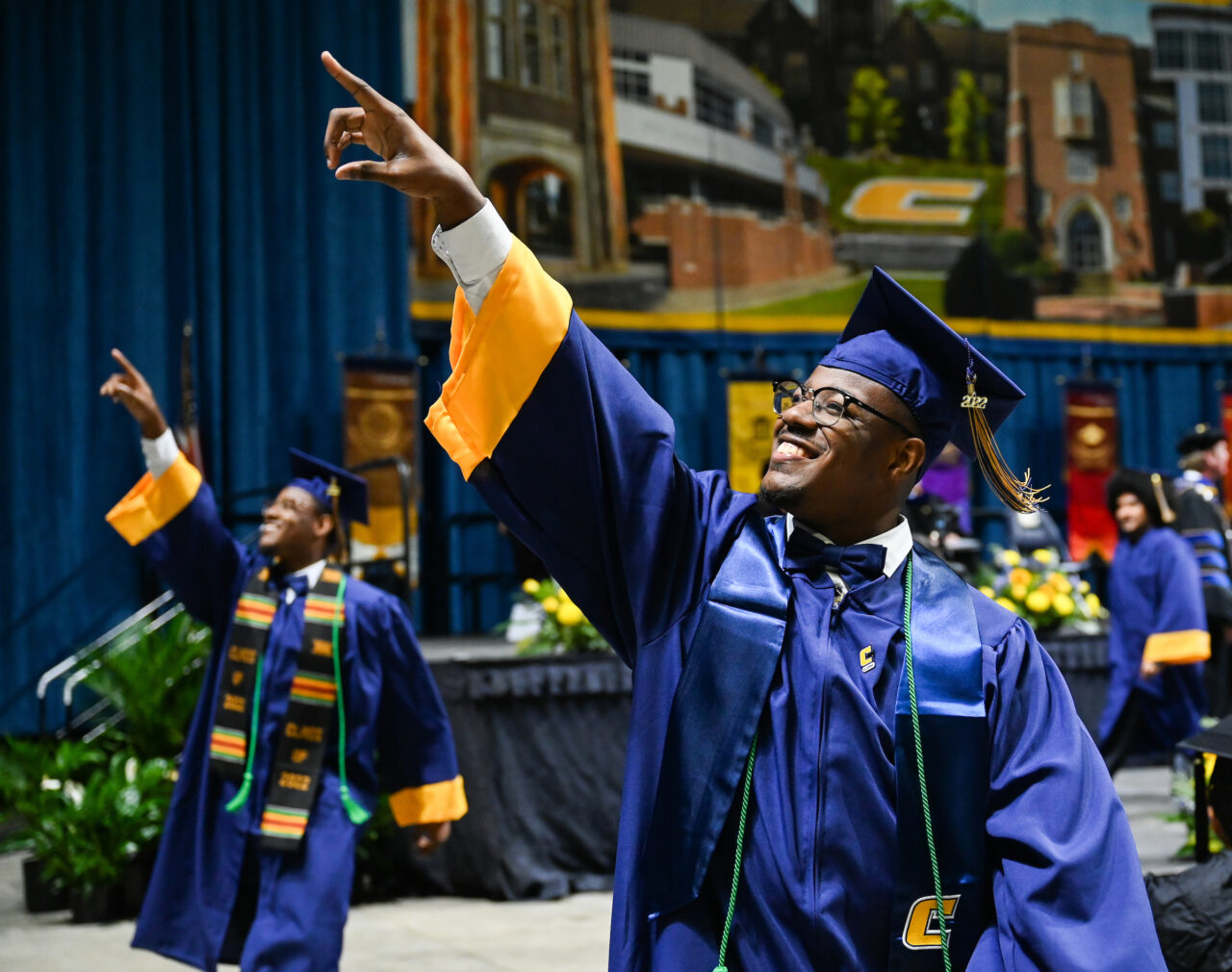 Chauncey, right, and Chris Figgures, two of a set of triplets, point to family members while exiting the stage at the first of two University of Tennessee at Chattanooga undergraduate commencement ceremonies on Saturday, Dec. 17, 2022 in McKenzie Arena. Caleb Figgures, not pictured, complete the trio.