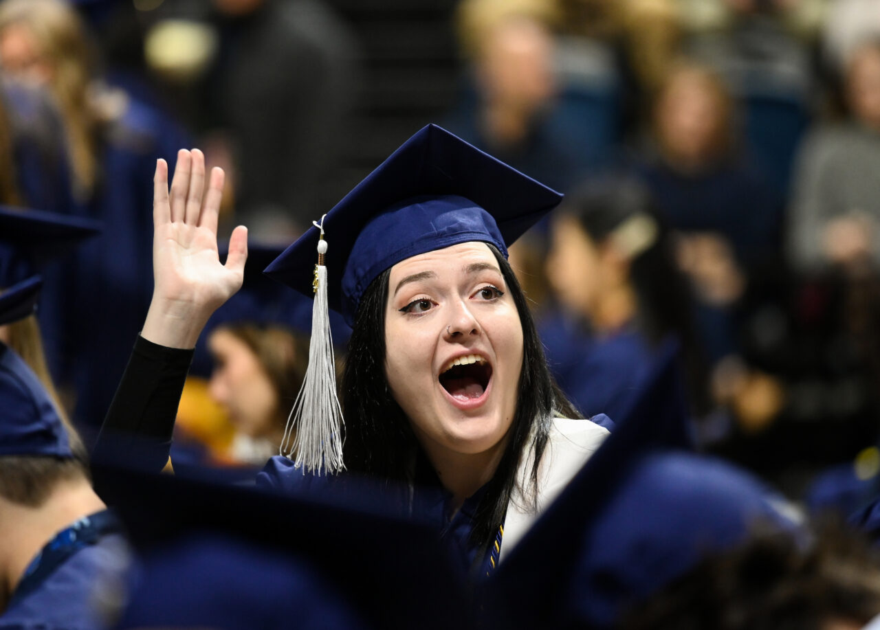 Aspen Freeman waves at family before the first of two University of Tennessee at Chattanooga undergraduate commencement ceremonies on Saturday, Dec. 17, 2022 in McKenzie Arena. Caleb Figgures, not pictured, complete the trio.