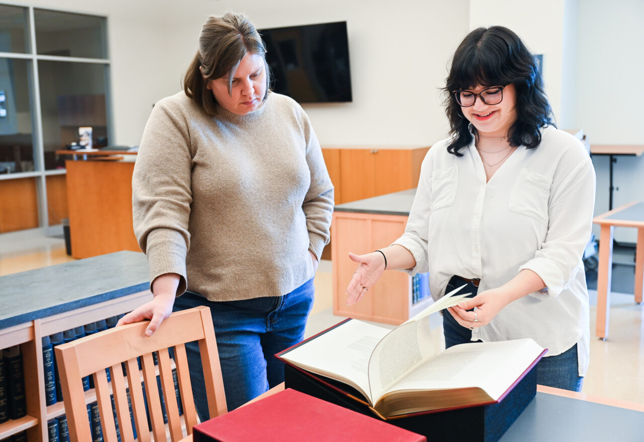 Carolyn Runyon, left, and Emily Ruiz show items from the Barry Moser collection on Monday, March 20. Photo by Angela Foster.
