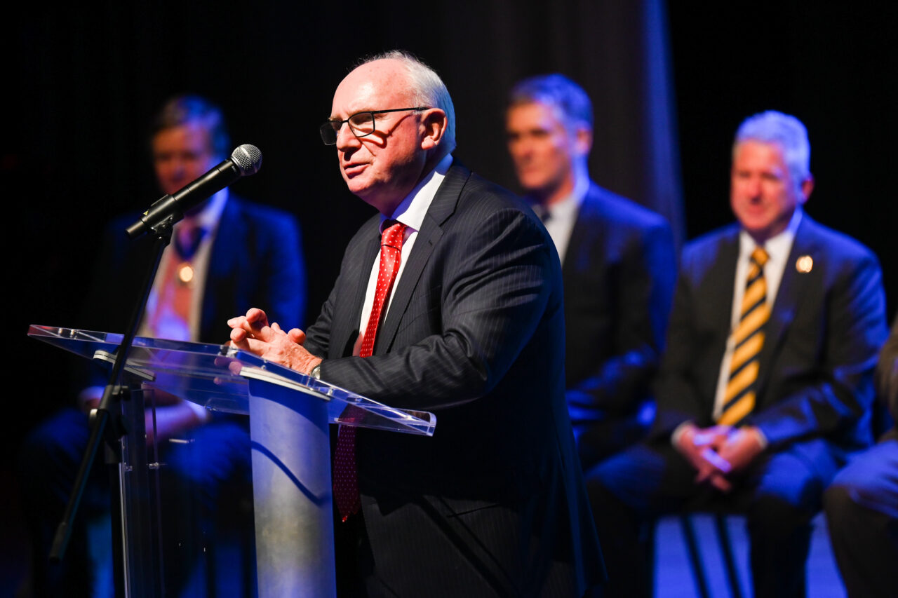 Bob Bone, parade founder and chair, talks Wednesday, March 22, 2023 in the Hayes Concert Hall before London officials present the Marching Mocs with their official invitation to participate in the London New Year’s Day Parade.